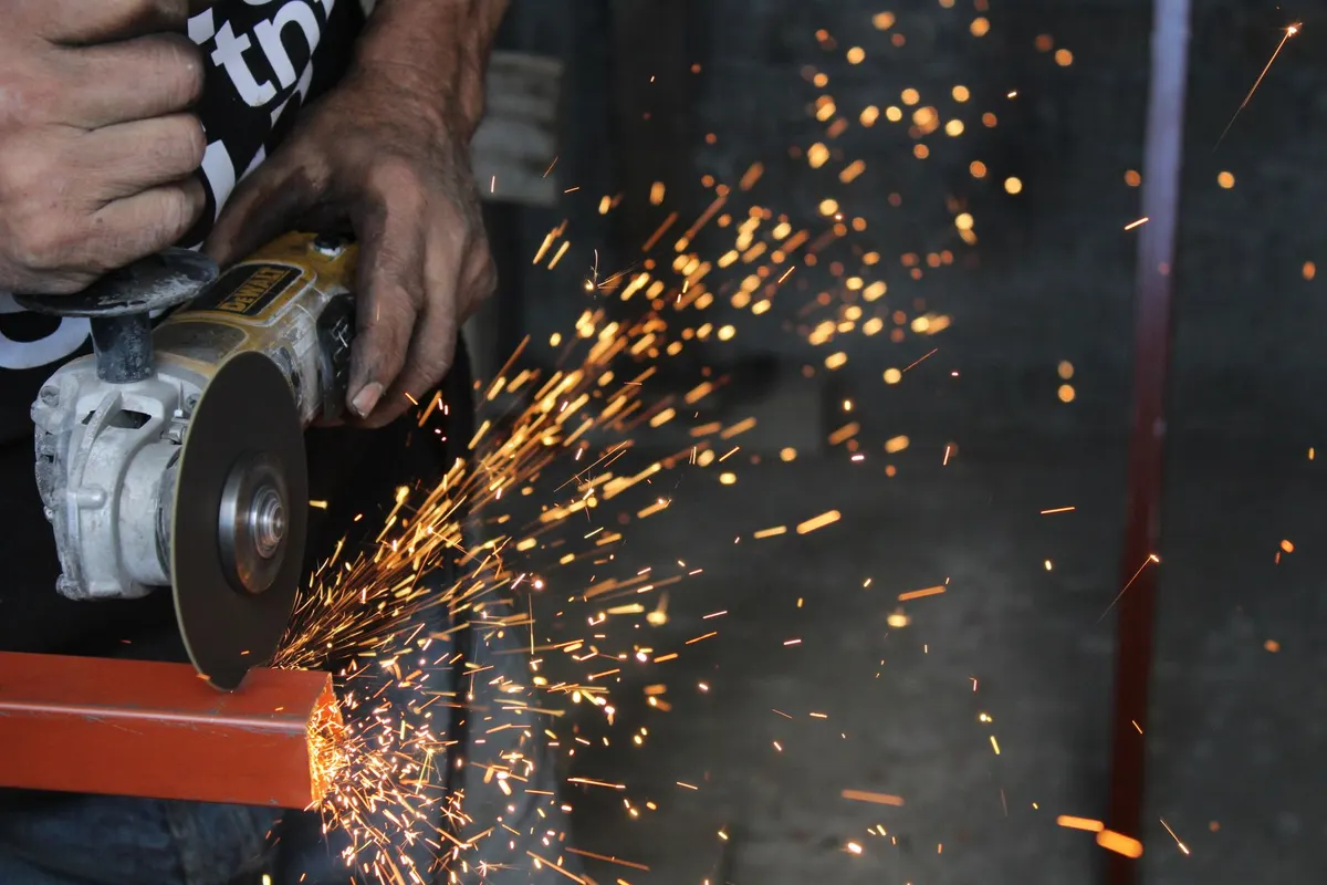 An angle grinder cutting through steel with sparks flying in a workshop