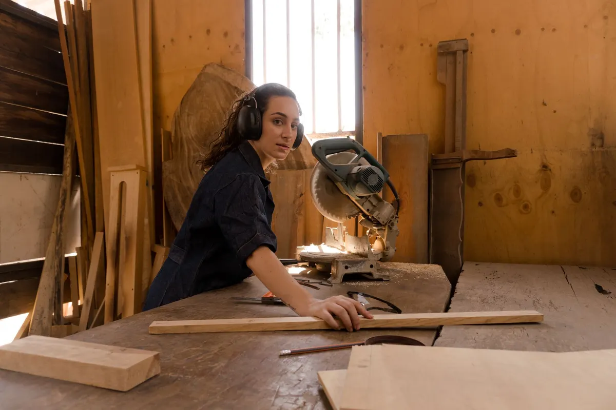 Compound miter saw crosscutting a length of wood trim molding in a carpentry workshop