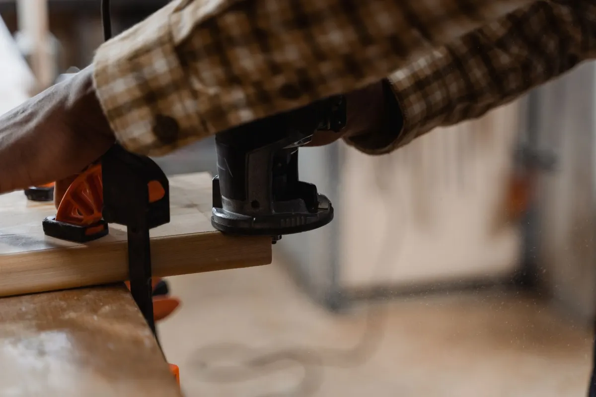 A handheld wood router cutting a decorative edge profile on a hardwood board