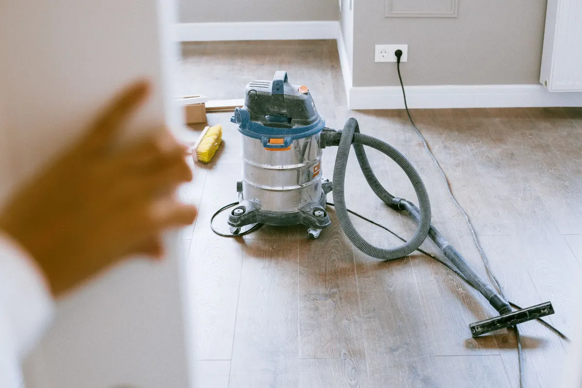 A shop vacuum collecting sawdust on a workshop floor next to a workbench
